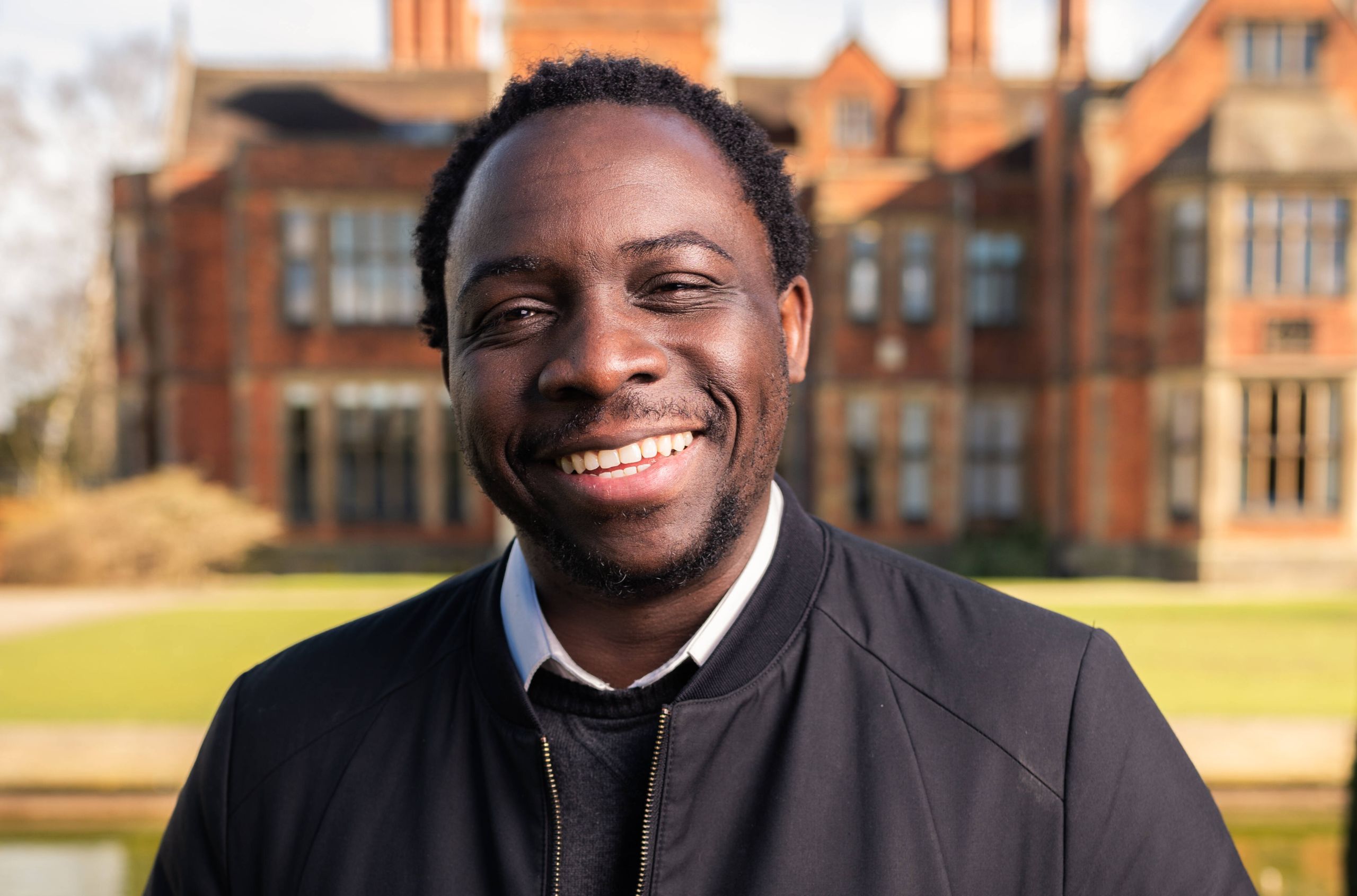 One of the University's scholars stands in front historic Heslington Hall